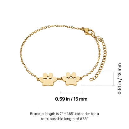 Gold chain bracelet with two small paw-shaped charms, shown on a white background with measurement annotations indicating the bracelet dimensions and total length.
