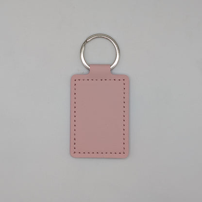 A rectangular pink leather keychain tag with stitched borders and a silver metal key ring, centered on a light gray background.