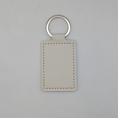 A blank rectangular leather keychain tag with a silver metal split ring, shown on a neutral light gray background.