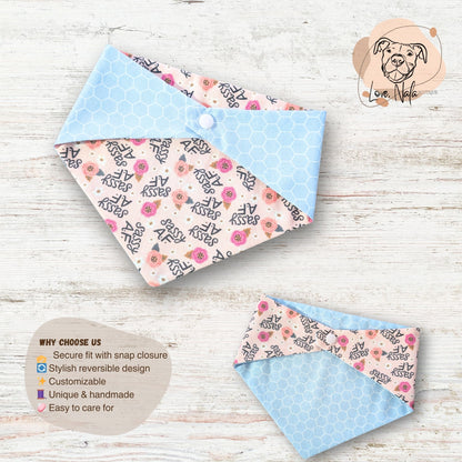 Two reversible dog bandanas with floral and text patterns on a wooden surface.