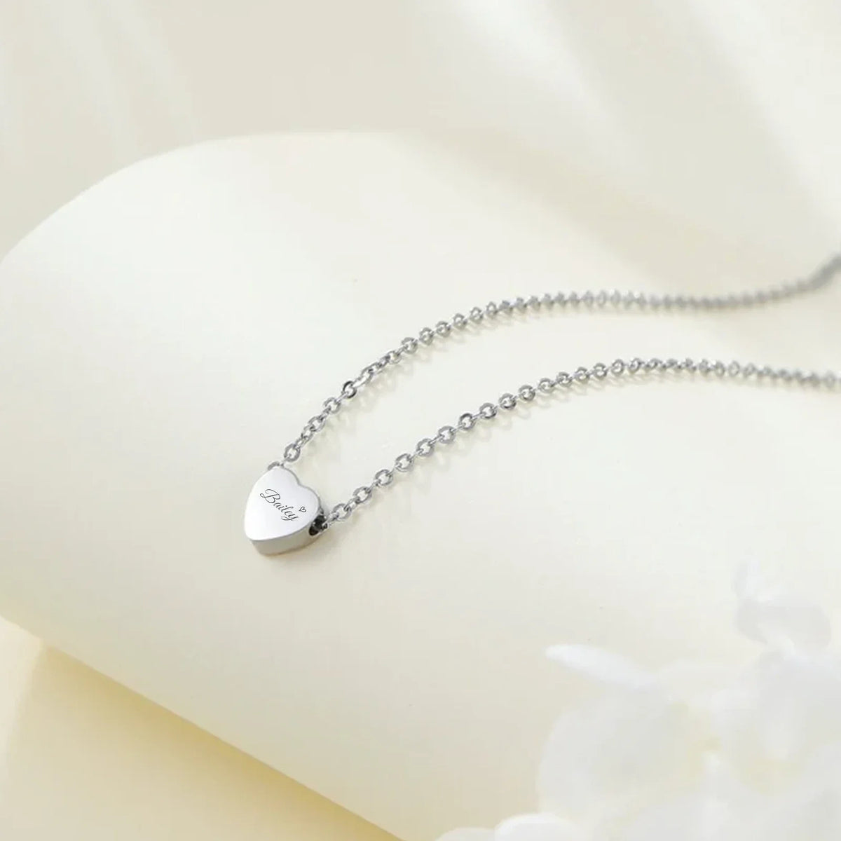 Silver necklace with a heart-shaped pendant on a white background