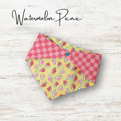 Playful pet bandana featuring a cute watermelon design with a pink checkered print on the reverse side