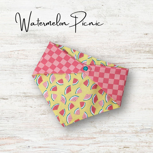 Playful pet bandana featuring a cute watermelon design with a pink checkered print on the reverse side
