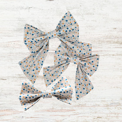 Three floral-patterned pet bows on a light wooden surface
