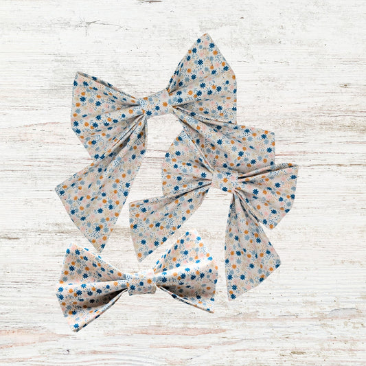 Three floral-patterned pet bows on a light wooden surface