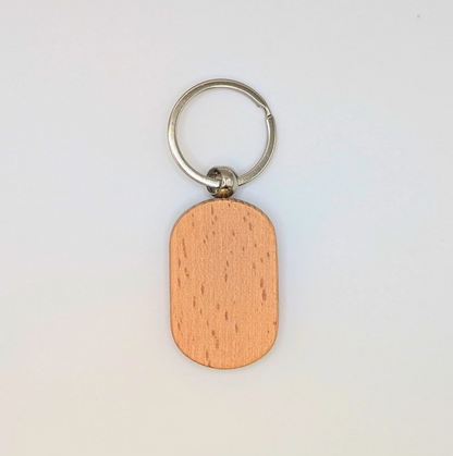 A minimalist keychain featuring a smooth, oval-shaped wooden tag with a natural wood grain finish and a silver metal split ring, shown on a plain white background.
