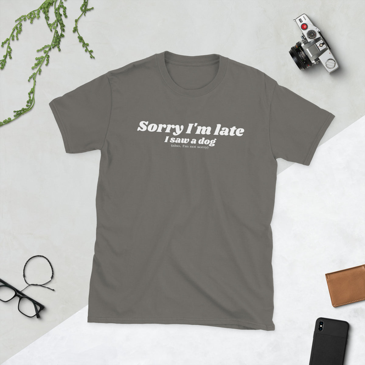 Product mockup of a t-shirt that says 'sorry I'm late I saw a dog. also I'm not sorry'. the shirt is grey